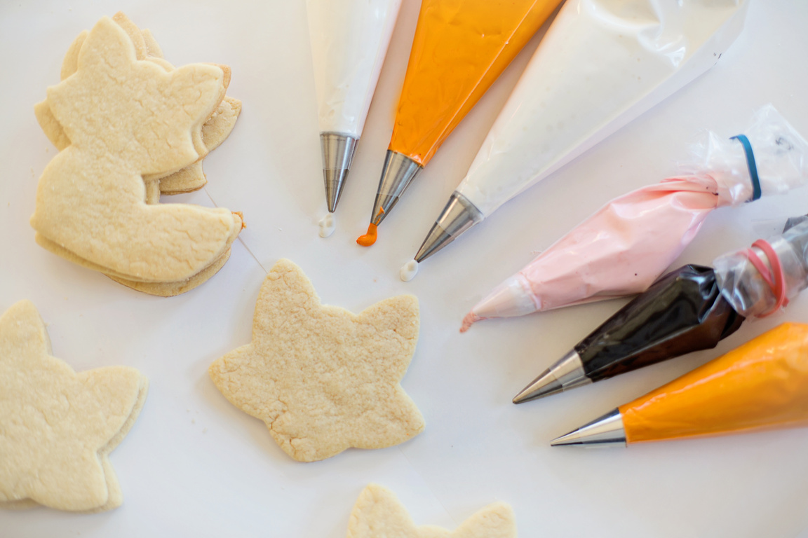 Piping Bag with Icing Beside Cookies on a White Surface