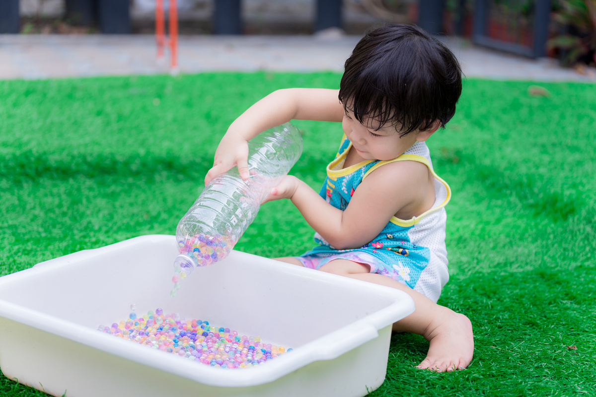 Boy Pouring Water Beads into a Basin